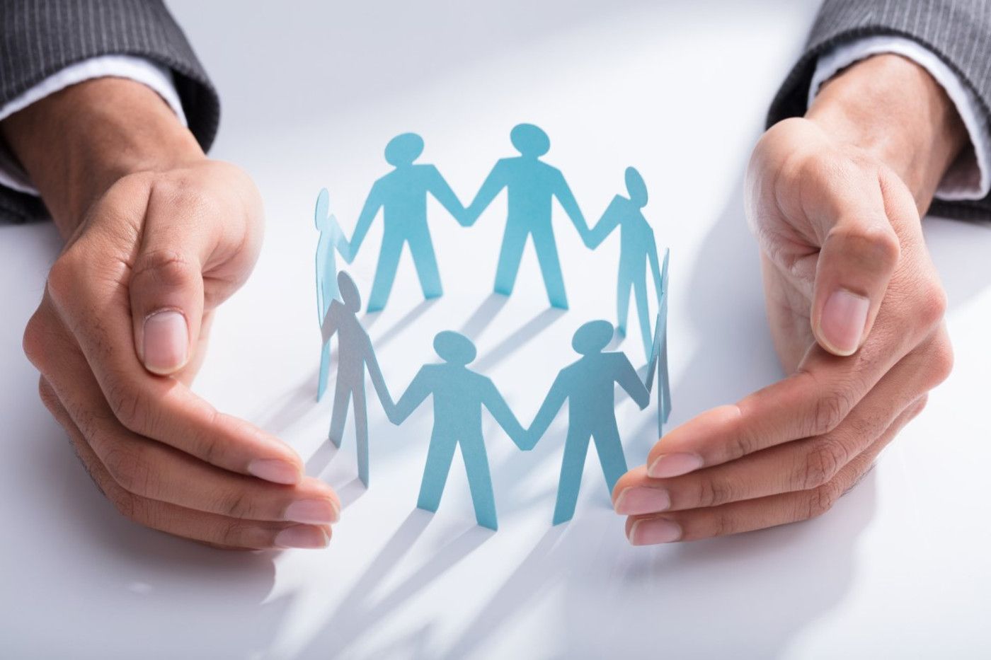 Hands protecting a circle of paper figures
